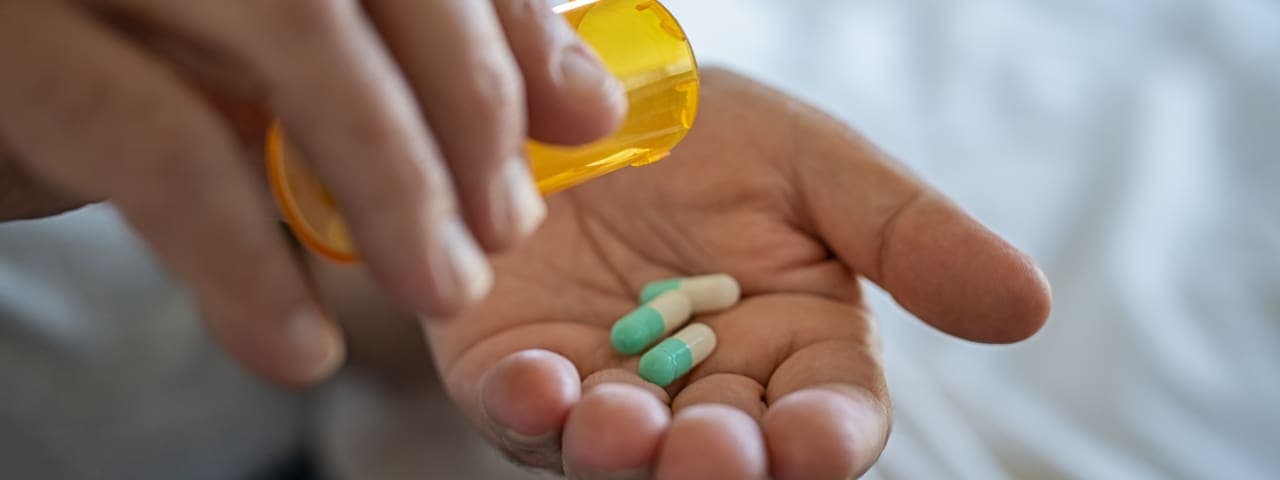 Closeup of man hand pouring capsules from a pill bottle into hand.